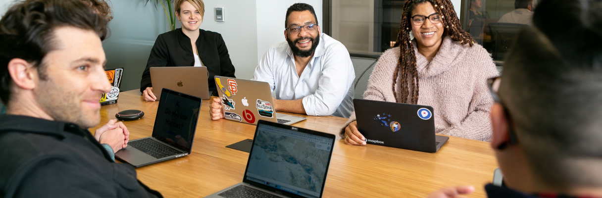 Imagem de pessoas sentadas na mesa, cada uma com um Notebook.